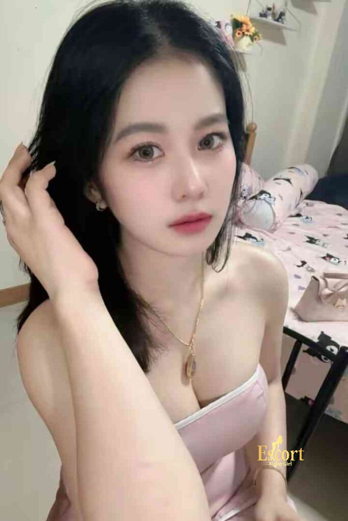 Escort Malay Girl Adeline, 22yo C Cup Thailand escort, sitting in a pink dress, posing for the camera KL Escort Girl Service
