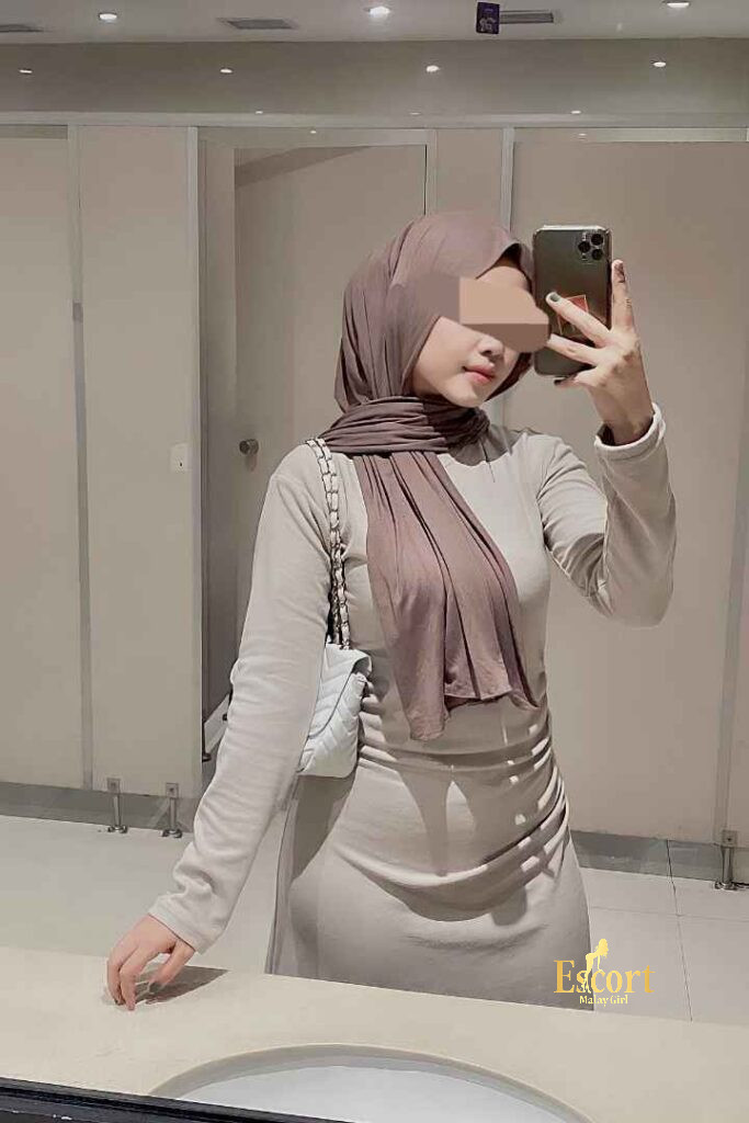 Escort Malay Girl Eika Malay escort in a bathroom, wearing a hijab and white dress, taking a selfie KL Escort Girl Service