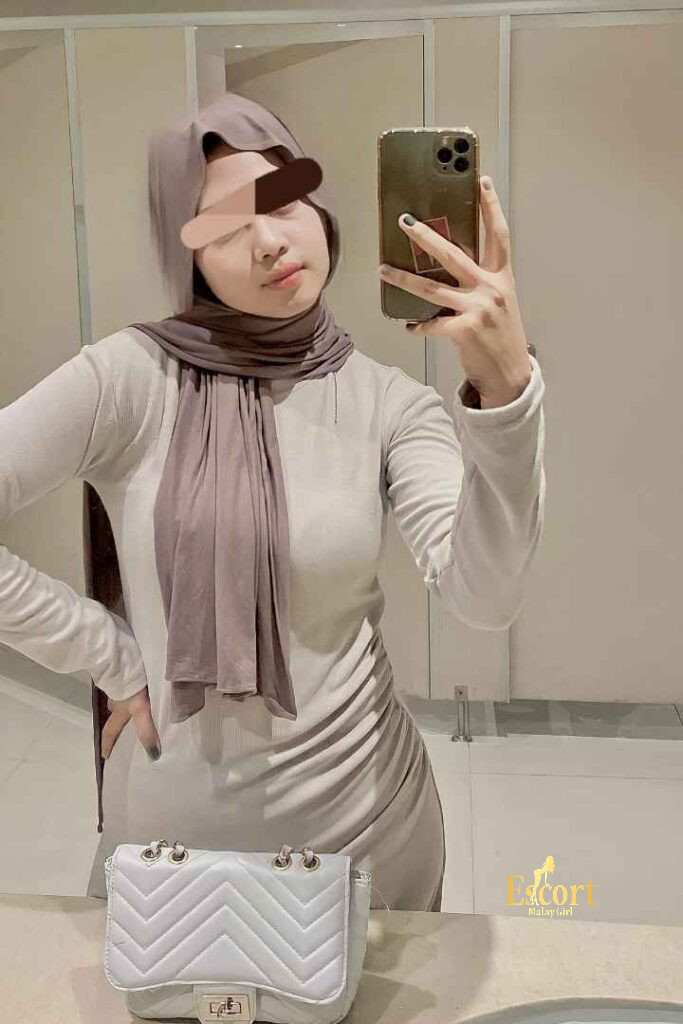 Escort Malay Girl Eika Malay Escort in a hijab, holding a phone, with a handbag KL Escort Girl Service