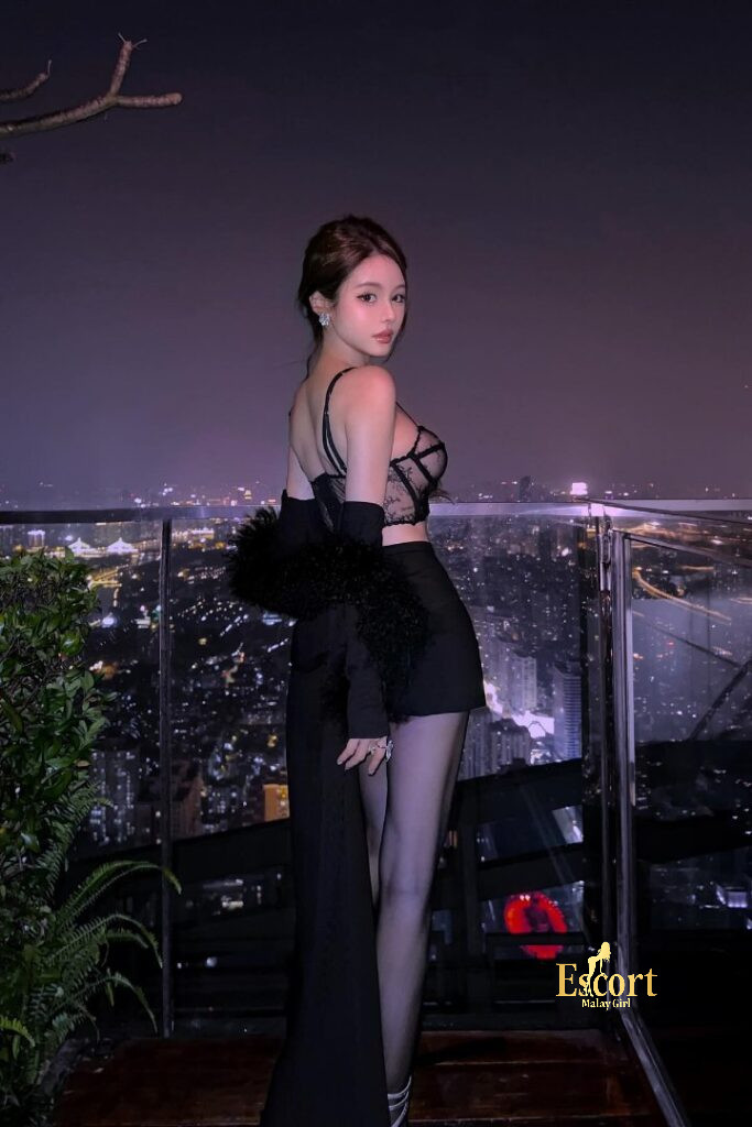 Escort Malay Girl Hui Mei Chinese Escort posing in black dress, looking at the night city skyline KL Escort Girl Service