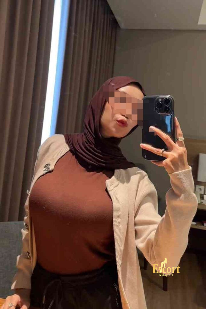 Escort Malay Girl Kirana, 23yo Malay escort in KL, taking a selfie in a beige cardigan and brown top. KL Escort Girl Service