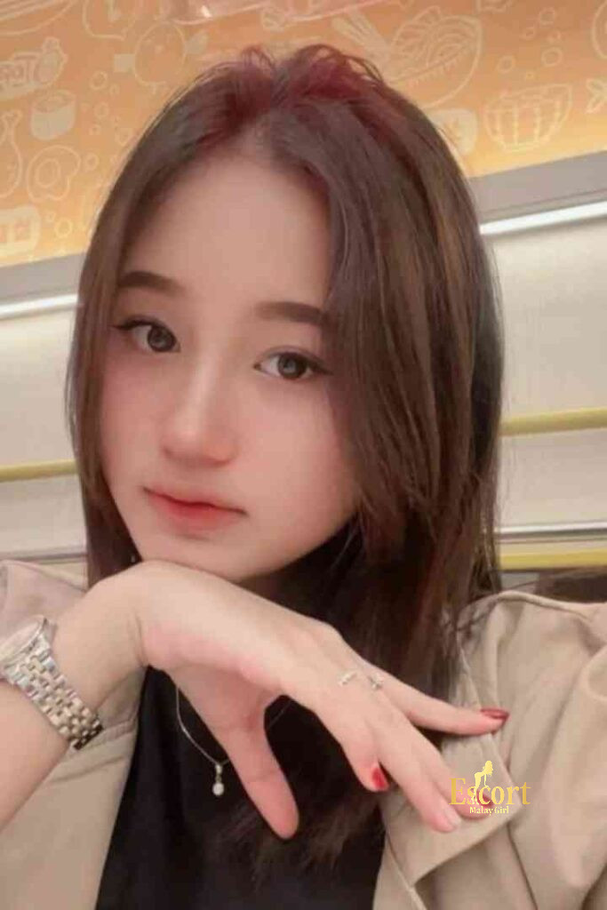 Escort Malay Girl Laila Malay Escort in KL with brown hair and red nails touching her chin KL Escort Girl Service