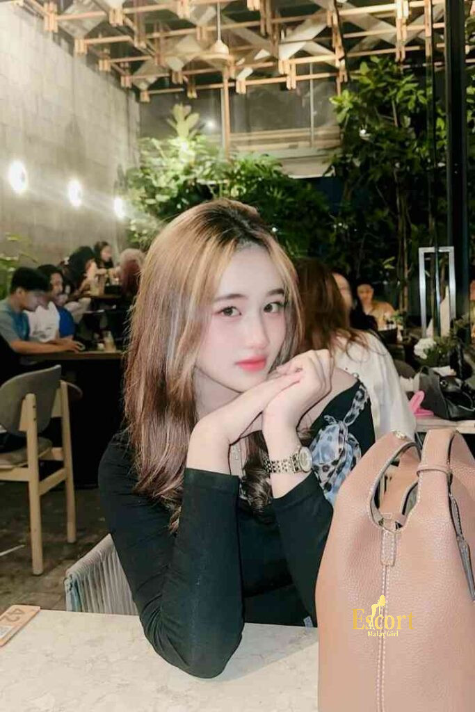 Escort Malay Girl Laila, a Malay escort girl in KL, poses with a handbag in a cafe KL Escort Girl Service