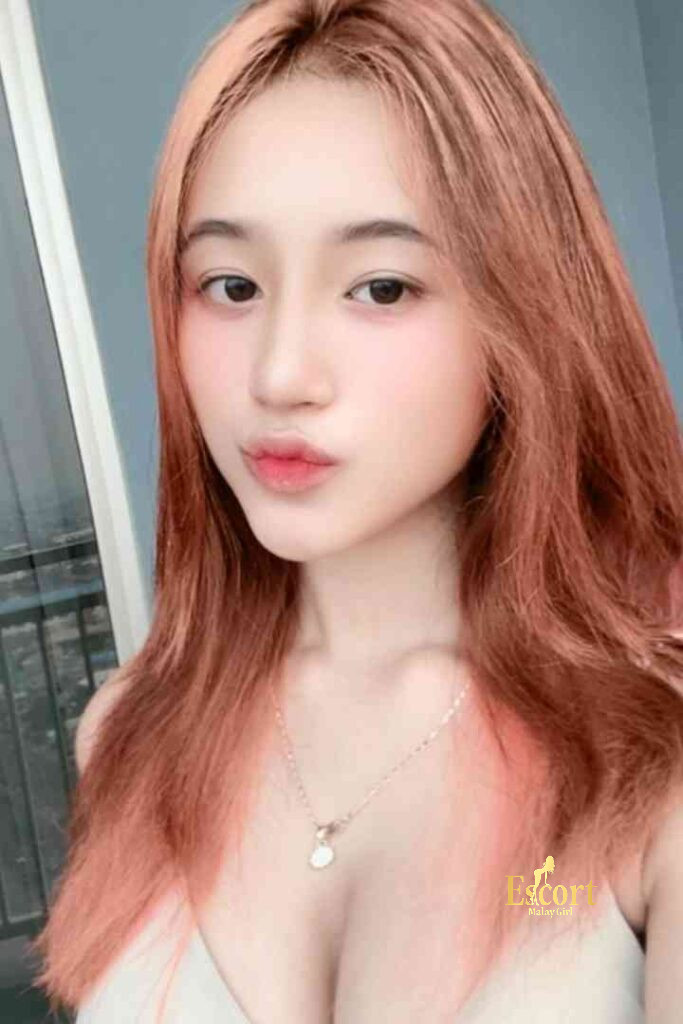 Escort Malay Girl Laila Malay Escort with red hair wearing a necklace and white top KL Escort Girl Service