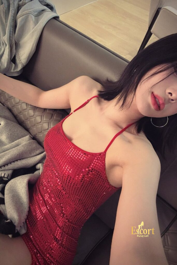 Escort Malay Girl Ling An, a 23yo Chinese escort in KL, wearing a red sequin dress, posing on a couch KL Escort Girl Service