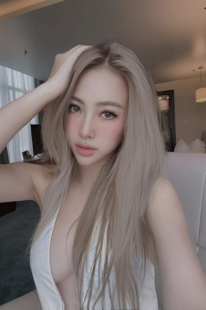 Escort Malay Girl Woman with blonde hair wearing a white top, looking at the camera. KL Escort Girl Service