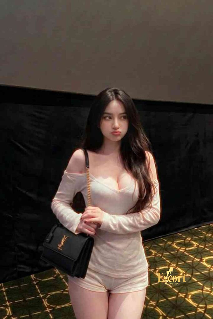 Escort Malay Girl Ummi, a 22yo C Cup Malay Escort in KL, stands with a black bag KL Escort Girl Service