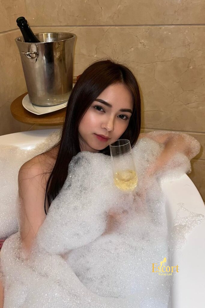 Escort Malay Girl Zanis, a 22-year-old Malay escort with B cup, relaxing in a bubbly bath, holding a champagne glass KL Escort Girl Service